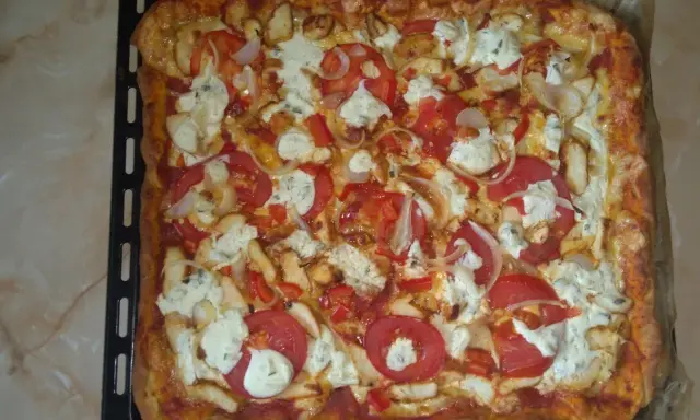 Pyszna, prostokątna pizza bez drożdży z kurczakiem, pomidorami, cebulą i serem.