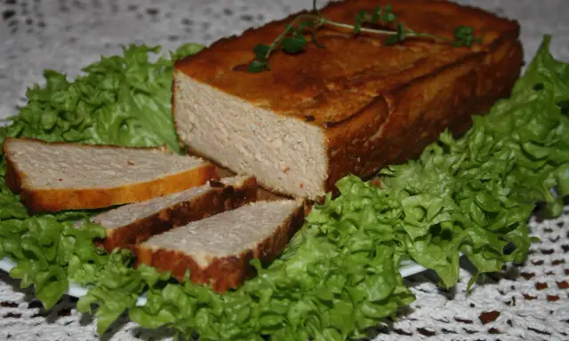 Pyszny pasztet drobiowy z wątróbką, pokrojony w plastry, podany na liściach sałaty. Idealny na kanapki.