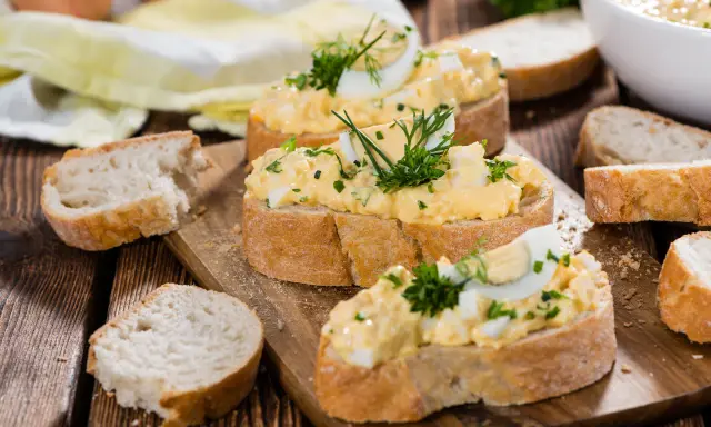 Kromki chleba z kremową pastą jajeczną na różne sposoby, ozdobione ziołami. Idealne na szybkie śniadanie lub przekąskę.
