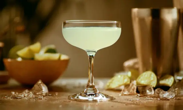 Orzeźwiający daiquiri w kieliszku, obok limonki i lodu. Idealny na upalne dni.