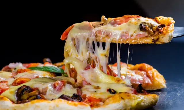 Rozciągający się ser z kawałka pysznej pizzy z kurczakiem, pomidorami i grzybami.