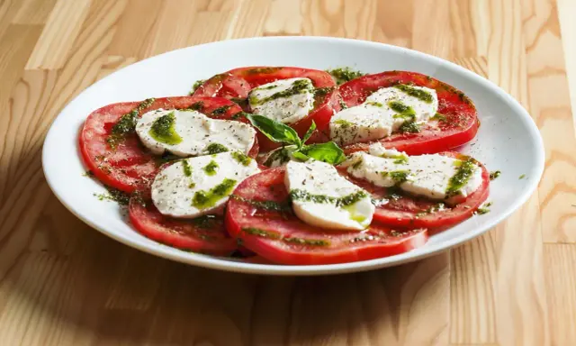 Sałatka caprese z pomidorów i mozzarelli, polana pesto. Idealne zdrowe przekąski na lato.