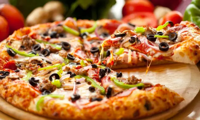 Gotowy spód do pizzy, z ciągnącym się serem, oliwkami, papryką i mięsem, aż chce się go włożyć do pieca!