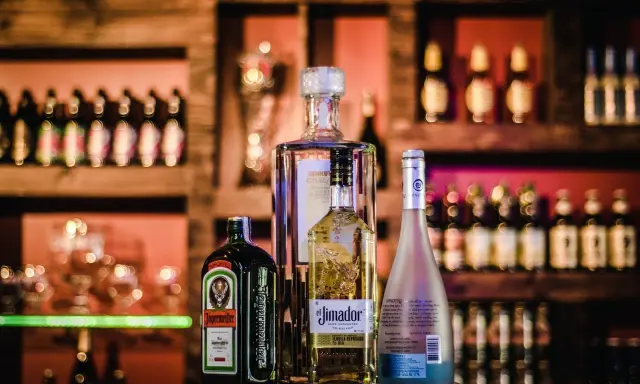 Jägermeister z sokiem jabłkowym i innymi alkoholami na barze.