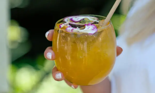 Orzeźwiający drink z marakują, ozdobiony kwiatami i plasterkiem owocu. Idealny na upalne dni.