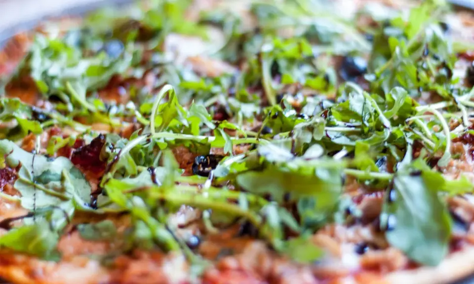 Pyszna pizza z tuńczykiem, rukolą i oliwkami, polana sosem balsamicznym. Idealna na szybki obiad.