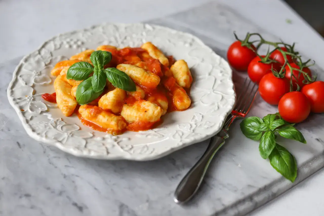 Pyszne gnocchi w sosie pomidorowym, ozdobione bazylią. Idealne na szybki obiad. Gnocchi przepis z czym podawać? Z pomidorami i bazylią!