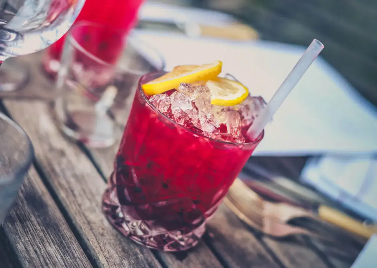 Orzeźwiający drink bezalkoholowy z grenadiną, lodem i plasterkami cytryny na drewnianym stole.