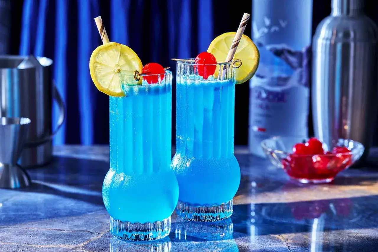 Dwa orzeźwiające drinki z blue curacao, ozdobione plasterkiem cytryny i wisienką, gotowe do podania.