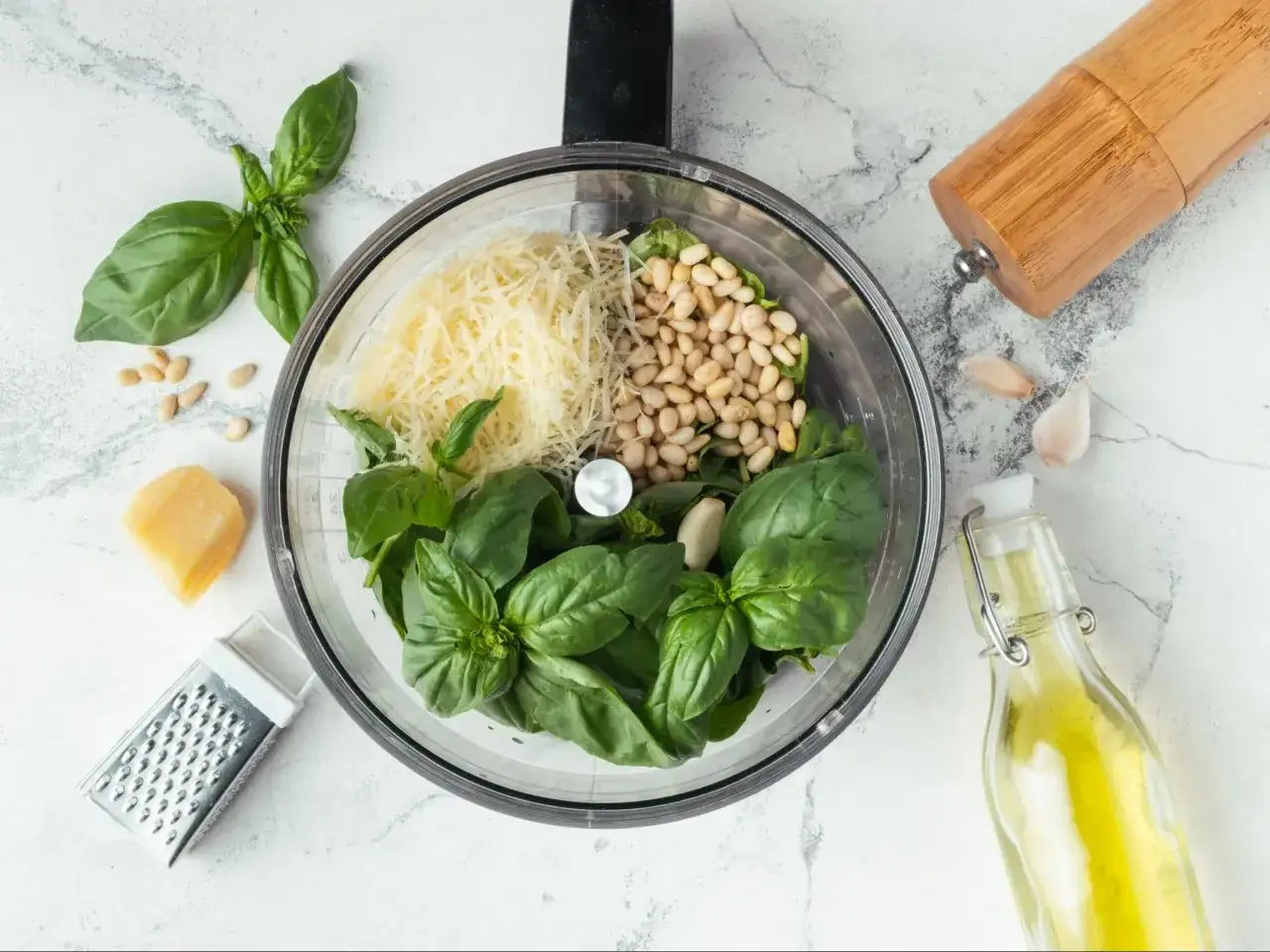 Składniki do pesto bazyliowego: świeża bazylia, orzeszki piniowe, parmezan, czosnek i oliwa.