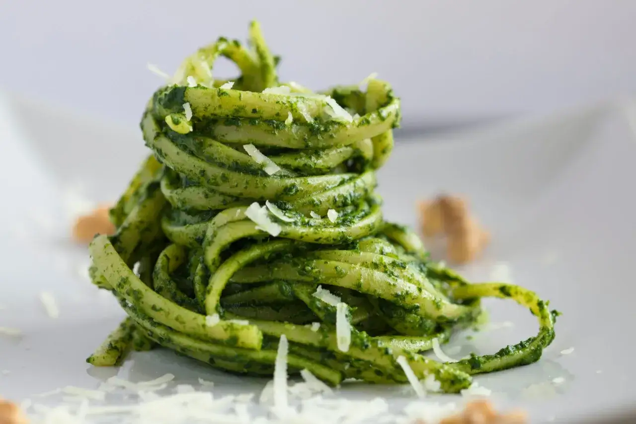 Makaron tagliatelle z aromatycznym pesto bazyliowym, posypany startym parmezanem.