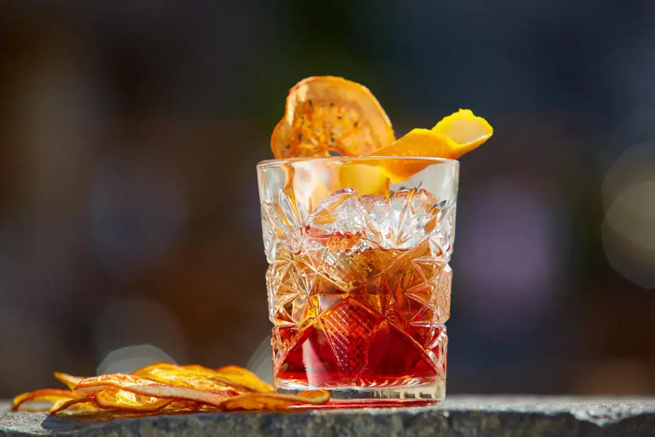 Klasyczny drink z lodem i skórką pomarańczy, ozdobiony suszonym owocem. Idealny old fashioned przepis.
