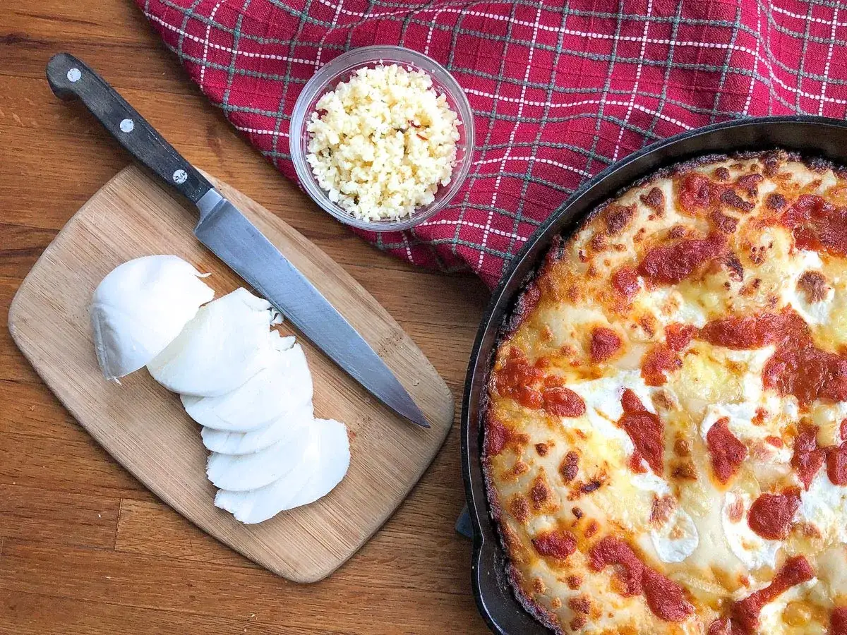 Gotowy ser na pizzę, pokrojona mozzarella i czosnek czekają na dodanie do pysznego dania.
