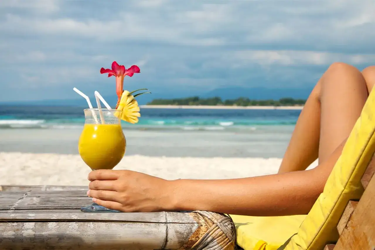 Idealny przepis na Sex on the Beach: żółty drink z ananasem i kwiatkiem, relaks na plaży.