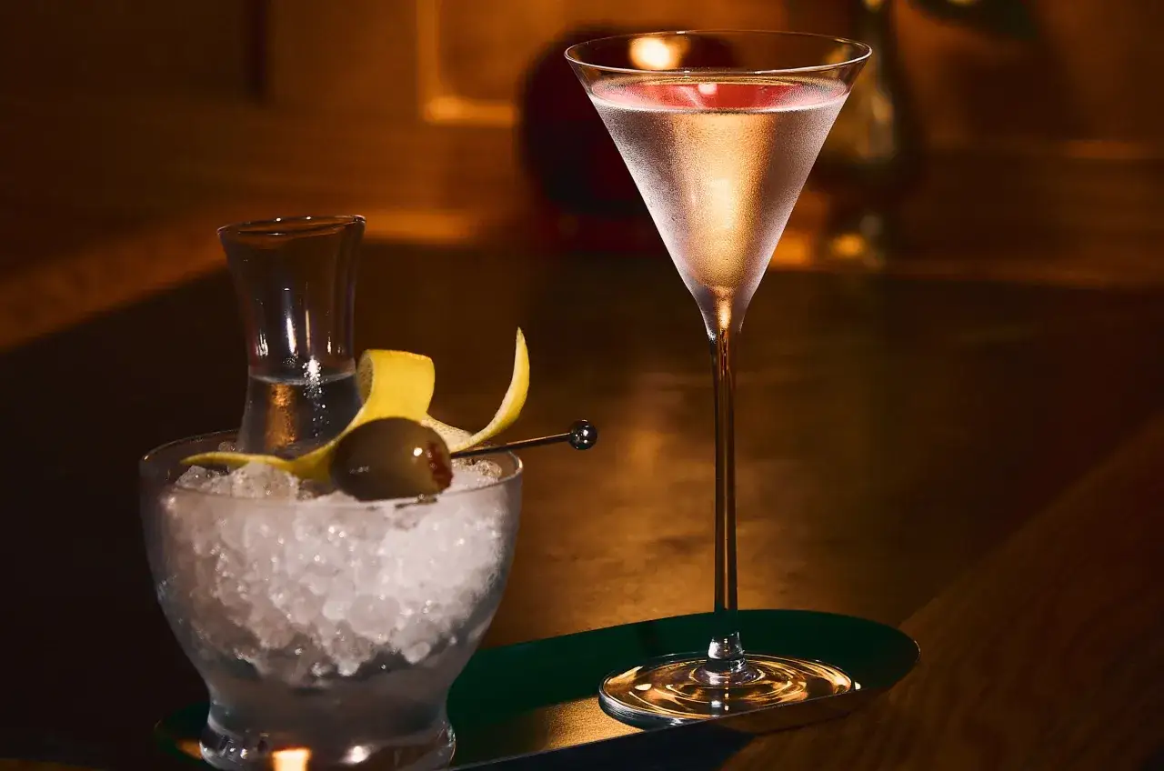 Eleganckie drinki z martini, jeden w kieliszku z lodem i oliwką, drugi w klasycznym kieliszku koktajlowym.