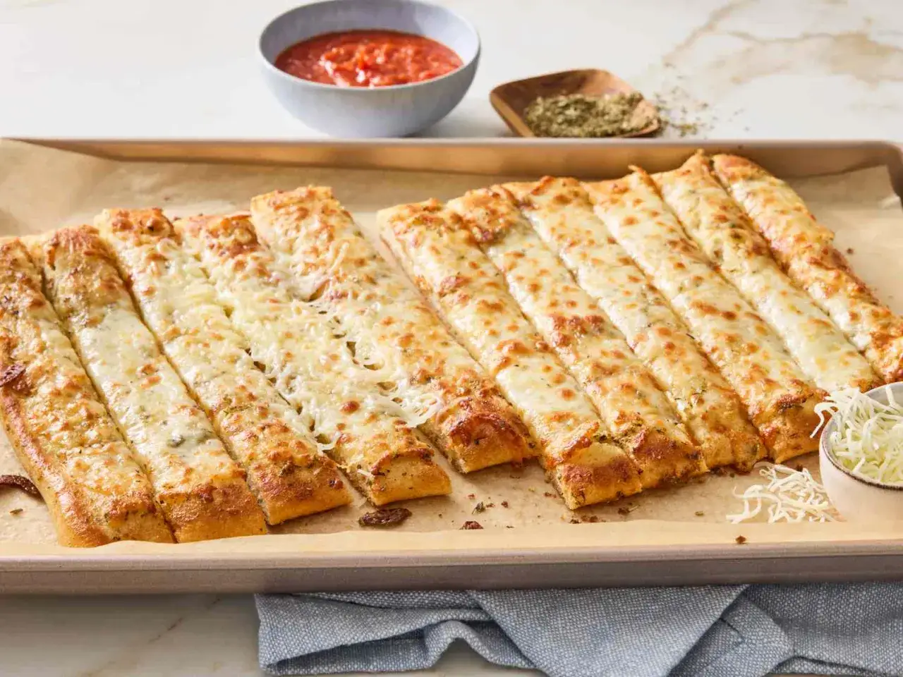 Pyszne paluchy z ciasta na pizzę, zapieczone z serem i ziołami. Idealne jako przekąska lub dodatek do sosu pomidorowego.