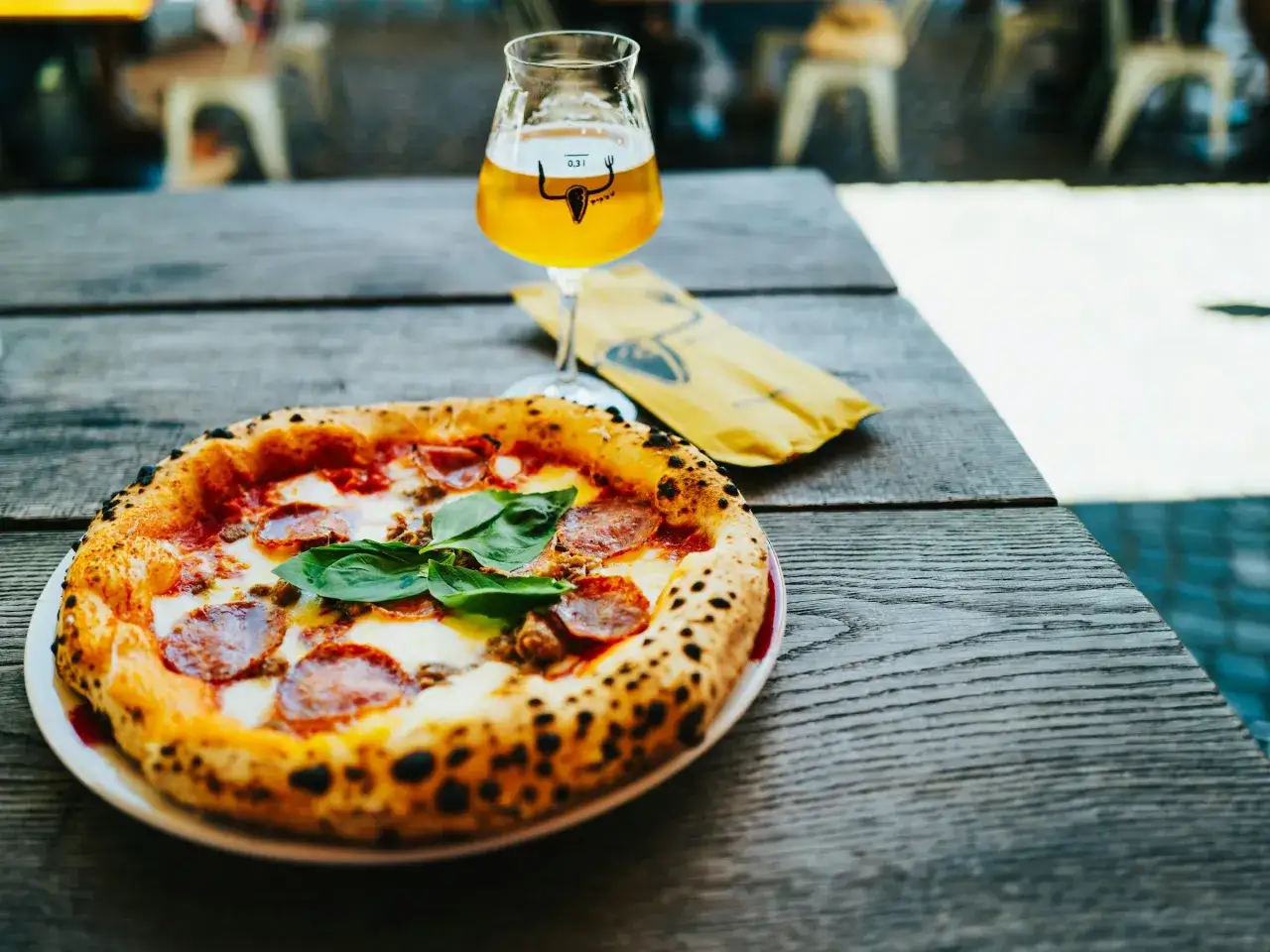 Pyszna pizza z salami i bazylią, idealnie komponuje się z orzeźwiającym drinkiem z piwem.