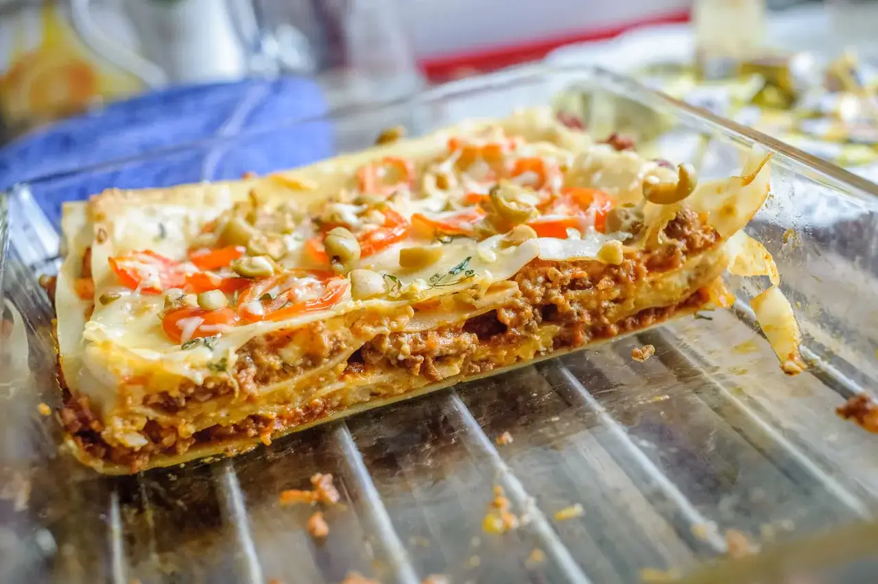 Pyszna, domowa lasagne jak z pieca, z warstwami mięsa, makaronu i sera, ozdobiona pomidorami i oliwkami.