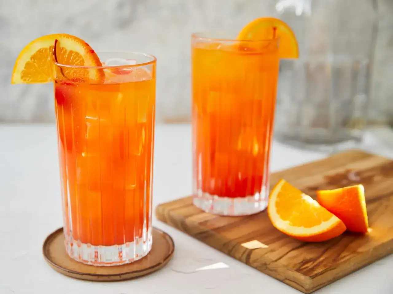 Dwa drinki tequila sunrise z pomarańczą i lodem, gotowe do podania.