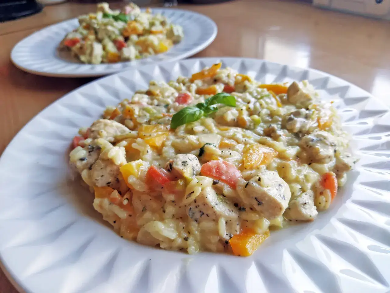 Pyszne risotto z warzywami i kurczakiem, udekorowane listkiem bazylii. Idealne na obiad.