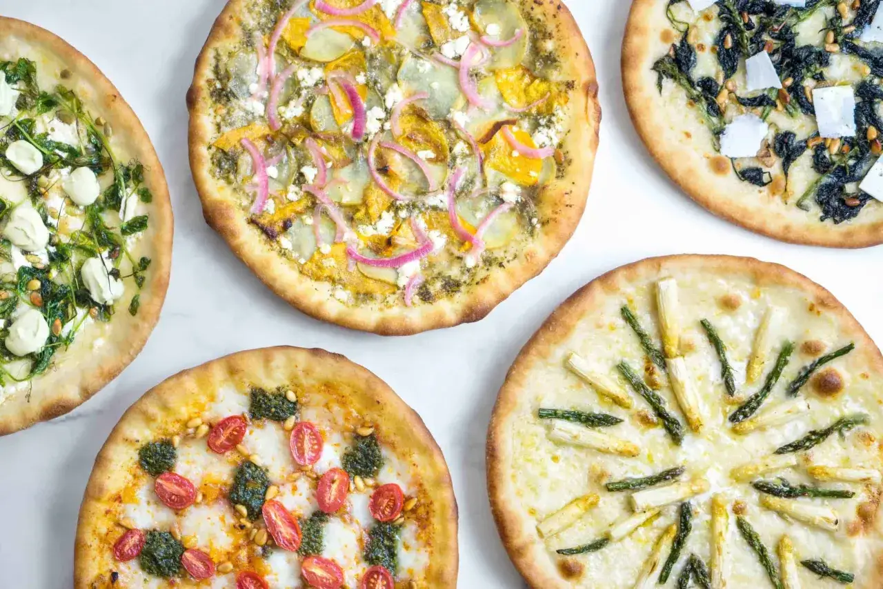 Pięć różnych pizz z nietypowymi dodatkami: szparagi, pomidorki, szpinak, dynia i ser. Idealne dodatki do pizzy dla każdego smakosza.