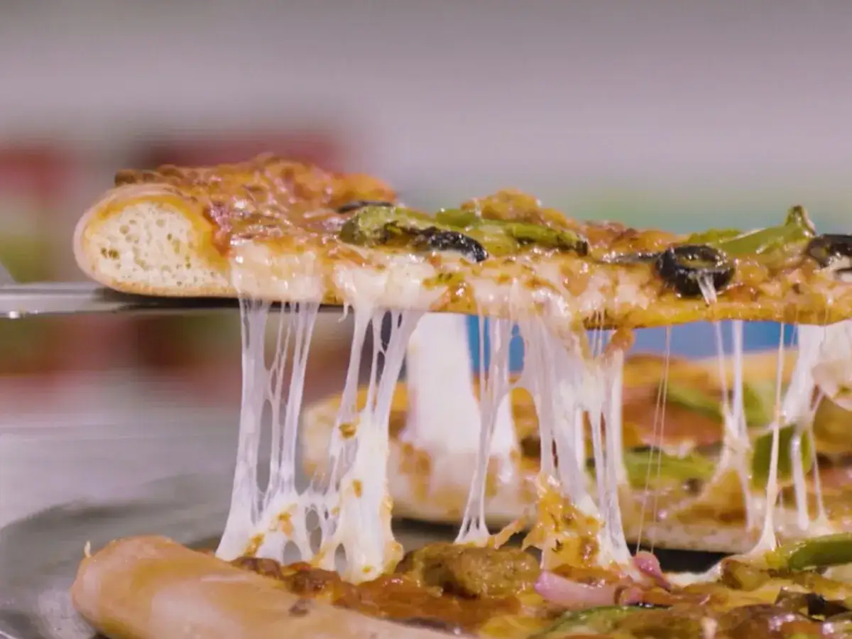 Rozciągający się ser z pizzy, która jest podnoszona łopatką. Czy pizza to fast food? Ta pyszna, gorąca pizza z pewnością kusi!