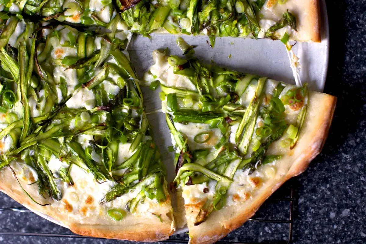 Pyszna pizza z zielonymi szparagami i ciągnącym się serem. Idealna na wiosenny obiad.