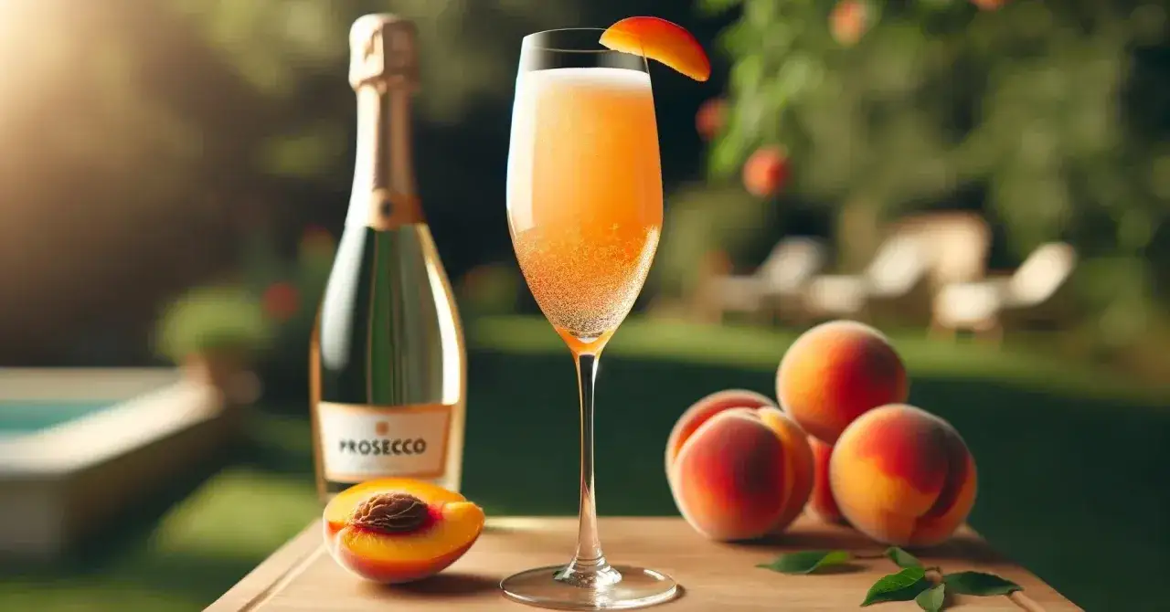 Orzeźwiający drink z likierem brzoskwiniowym, Prosecco i świeżymi brzoskwiniami na letnim przyjęciu w ogrodzie.