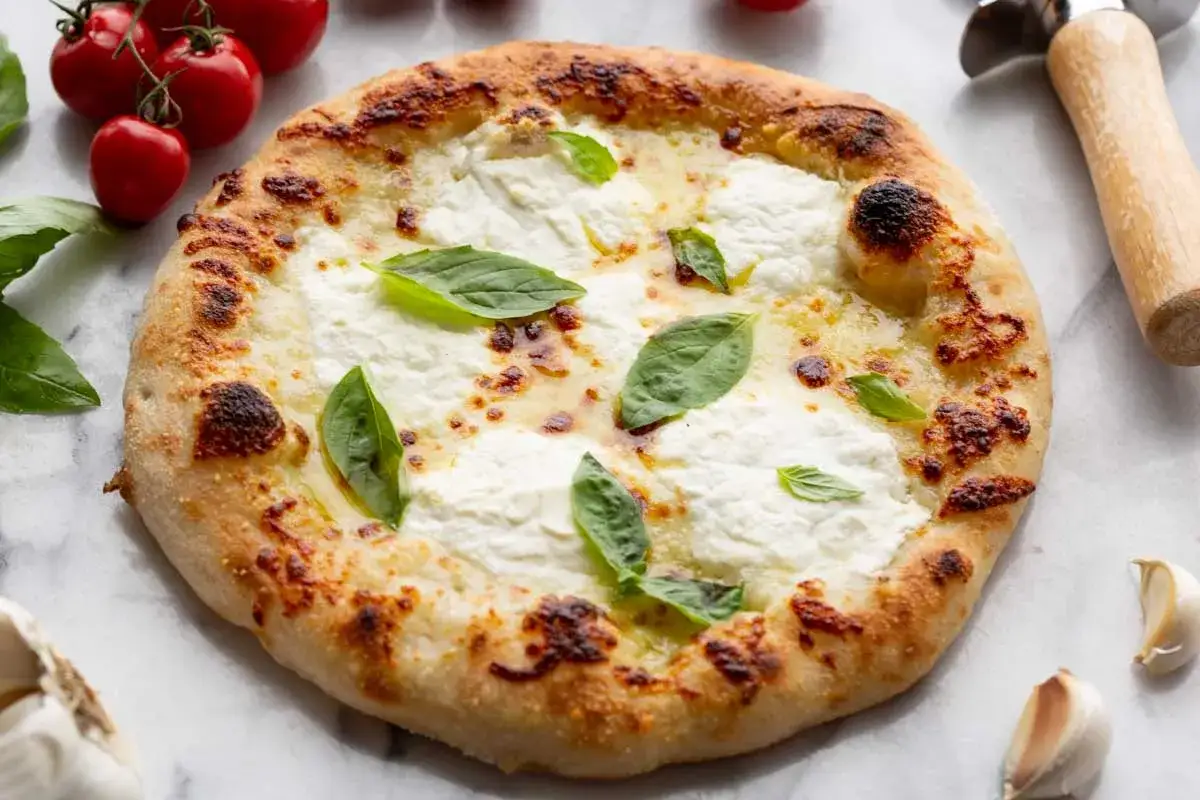 Pyszna pizza bianca z kremowym serem, świeżą bazylią i pomidorkami koktajlowymi. Idealna na szybki obiad.