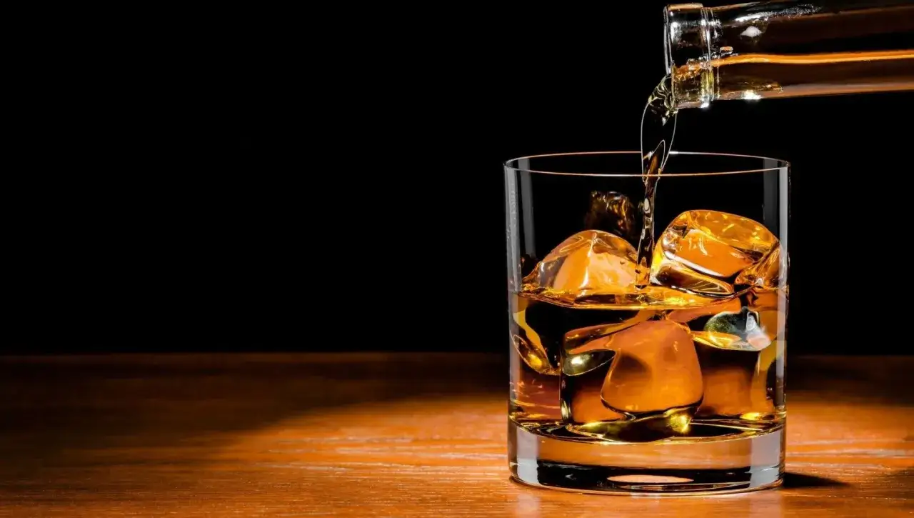 Szklanka z lodem, do której nalewana jest whisky. Idealne proporcje whisky z colą to sekret udanego drinka.