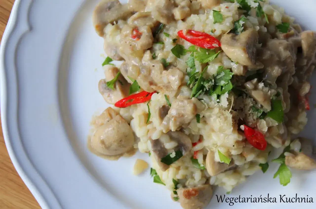 Kremowe risotto z pieczarkami, ozdobione natką pietruszki i papryczką chili. Pyszne danie wegetariańskie.