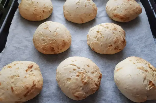 Świeżo upieczone bułki bez drożdży, lekko zarumienione, ułożone na papierze do pieczenia.