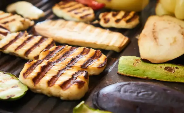 Grillowany ser halloumi z paskami od rusztu, obok cukinia, bakłażan i inne warzywa.